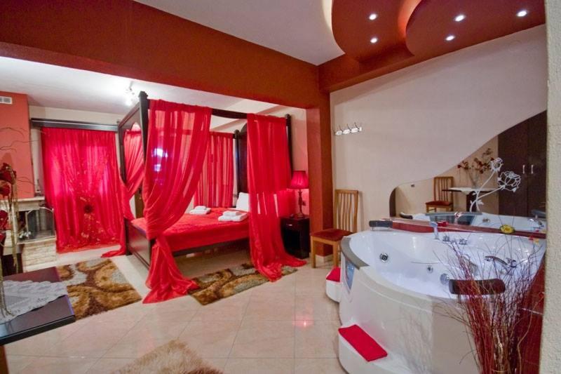 un bagno con vasca e un letto con tende rosse di Neraides a Kato Loutraki