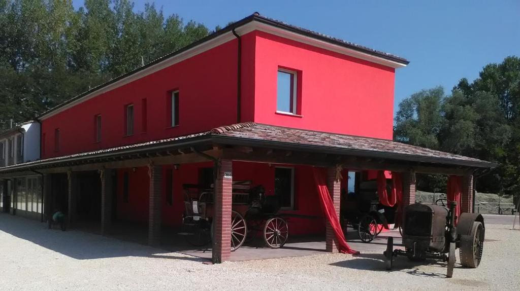 un edificio rojo con un coche aparcado delante de él en All'Antica Ruggine, en Alseno