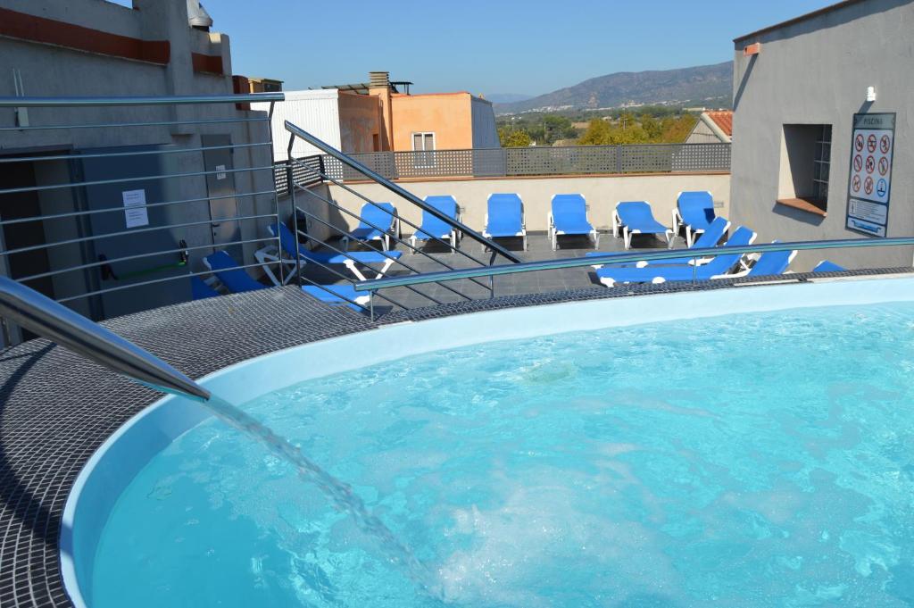 a swimming pool on top of a building with chairs at Hotel Ciutadella in Roses