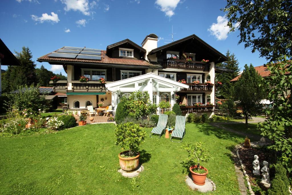 una casa grande con algunas sillas en el patio en HAUS Susanne - TOP-Ferienwohnungen - SOMMER-Bergbahn inklusive, en Obermaiselstein