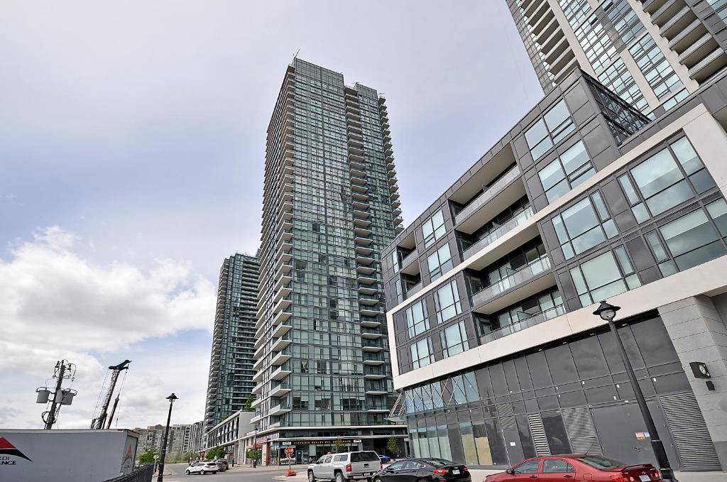 a tall building with cars parked in front of it at Royal Stays Furnished Apartments - Missisauga City Centre in Mississauga