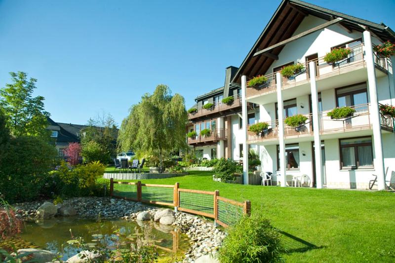 ein Gebäude mit einer Bank vor einem Teich in der Unterkunft Haus Alexandra inkl MeineCard Plus in Willingen