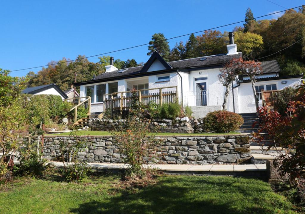 a white house with a stone wall at Ivybank Cottage in Lochgoilhead