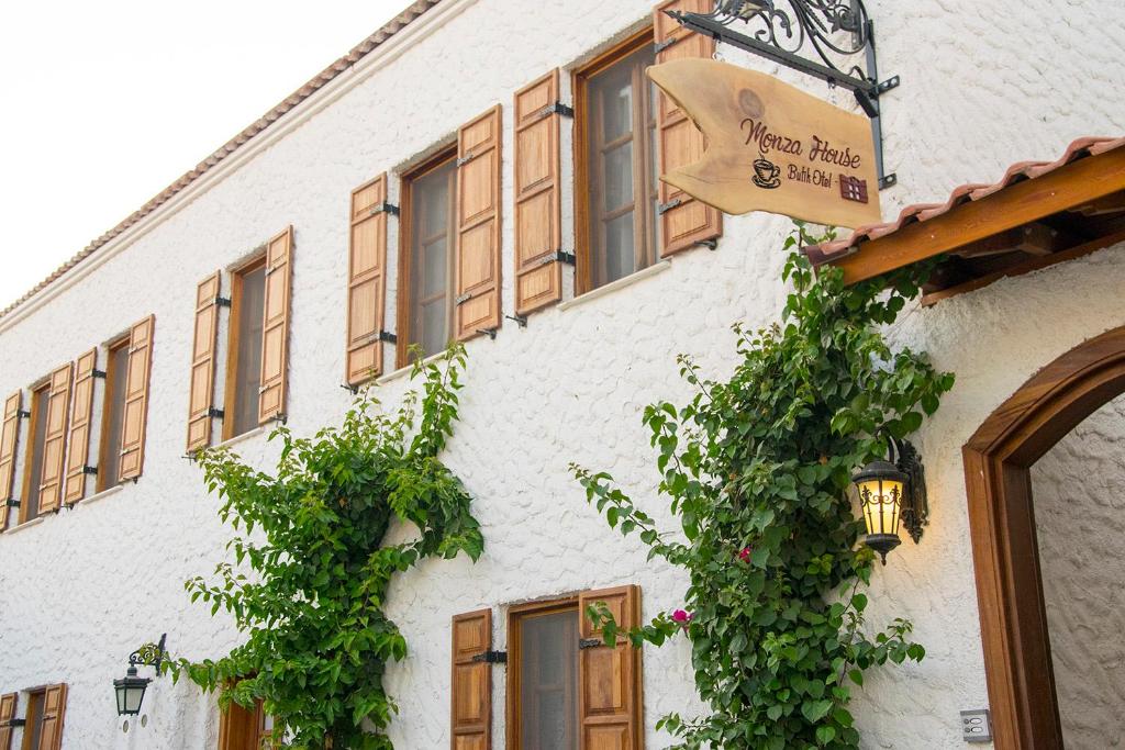 a white building with a sign on the side of it at Monza House Otel in Siğacık