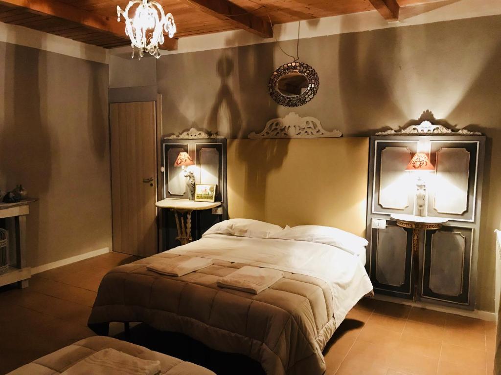 1 dormitorio con 1 cama, 2 espejos y lámpara de araña en Cascina la castagnara, en Oriolo