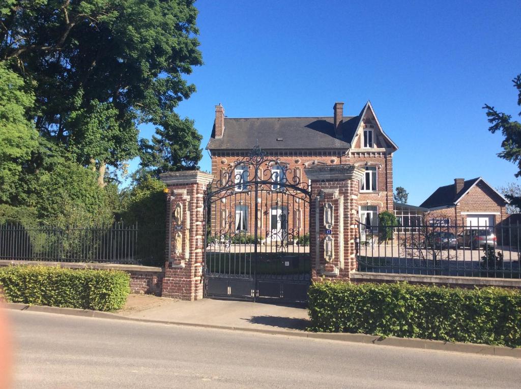 een oud stenen huis met een smeedijzeren hek bij L'hostellerie du chateau in Mesnil-Saint-Nicaise