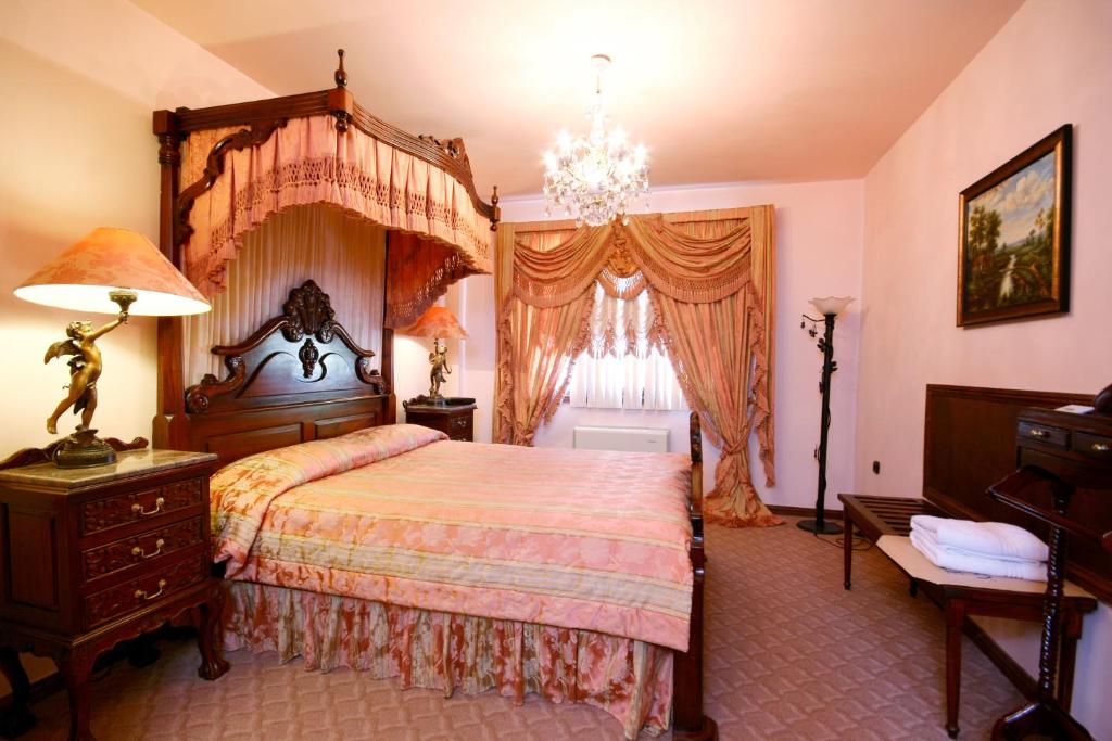 a bedroom with a large bed and a chandelier at Villa Dallas Residence - Airport shuttle in Varna City