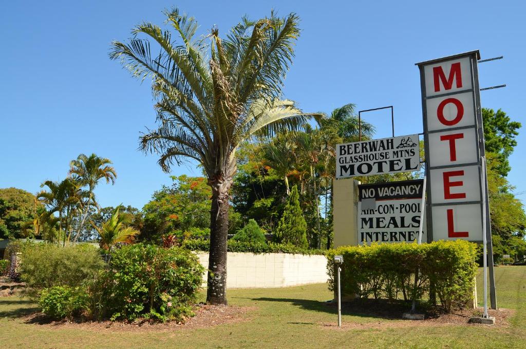 een bord voor een motel naast een palmboom bij Beerwah Glasshouse Motel in Beerwah