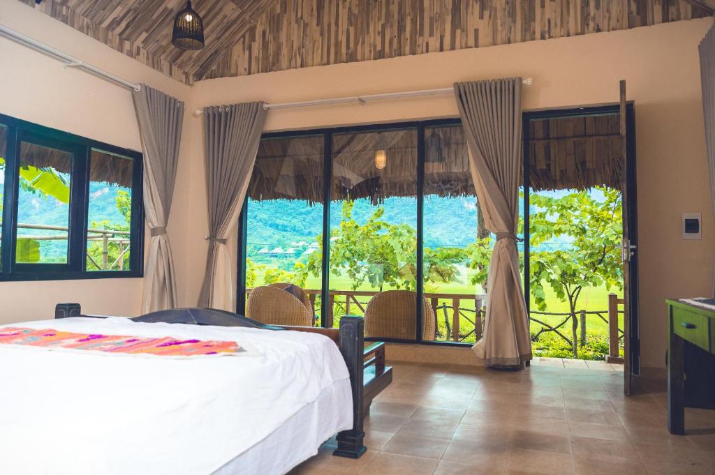 a bedroom with a bed and a large window at Mai Chau Moment Spa & Resort in Mai Chau