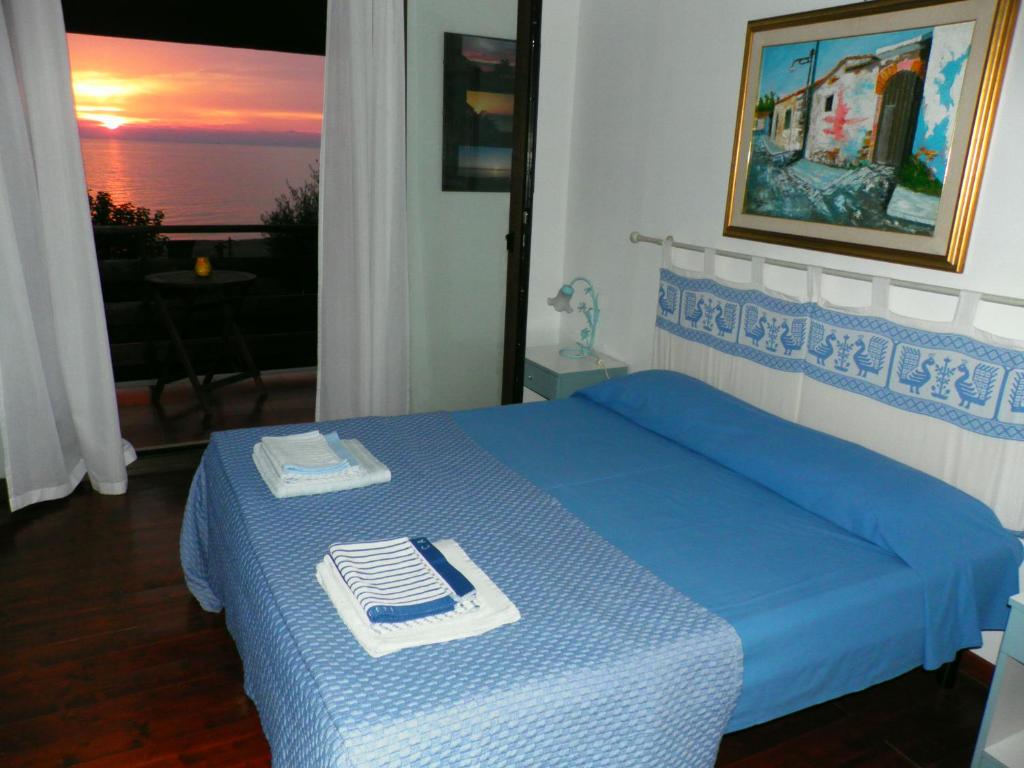 a bedroom with a blue bed with a view of the ocean at Ajò Faci a Mari in Capoterra