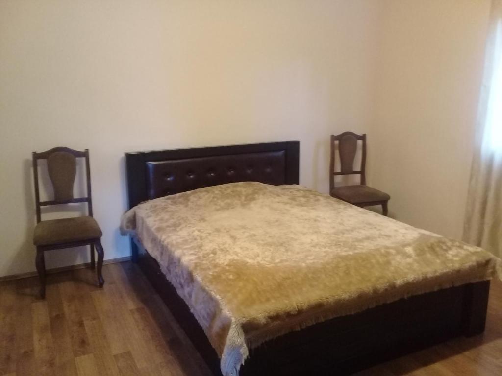 1 Schlafzimmer mit einem Bett und 2 Stühlen in der Unterkunft Guest House Gikacha in Tbilisi City