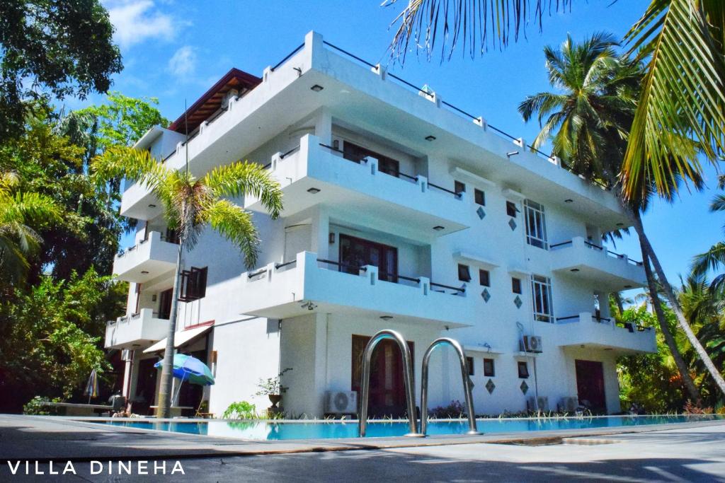 a white building with a pool in front of it at Villa Dineha in Hikkaduwa