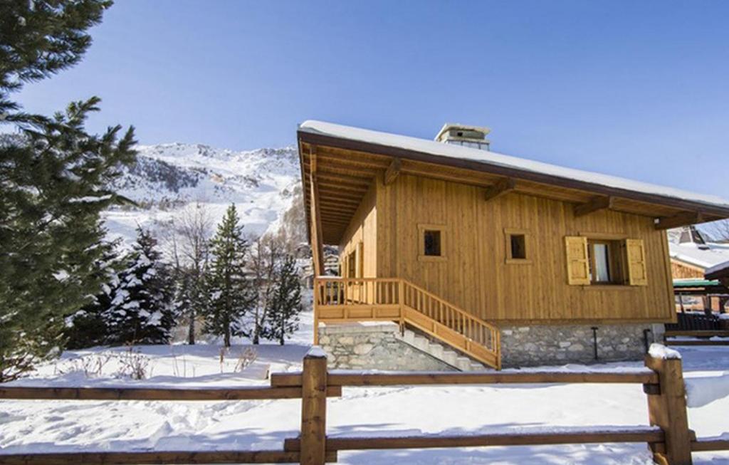 uma cabana de madeira na neve com uma cerca de madeira em Odalys Chalet Le Cabri em Val dʼIsère