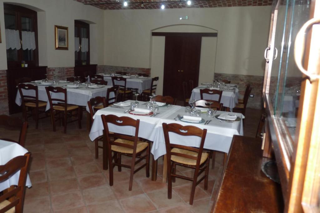 uma grande sala de jantar com mesas e cadeiras brancas em Agriturismo Maria Cristina em Treiso