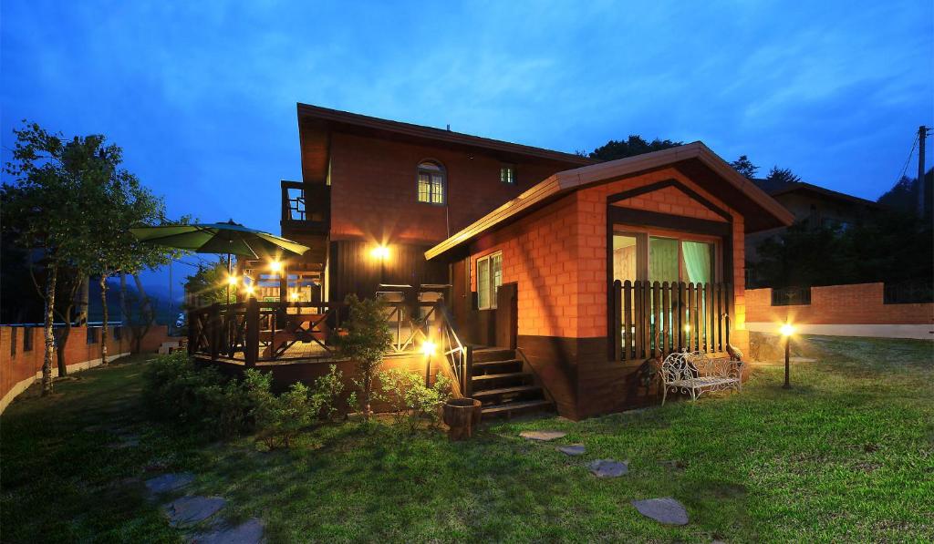 a tiny house with a porch and an umbrella at Daegwanryeong Rodem Tree Pension in Pyeongchang
