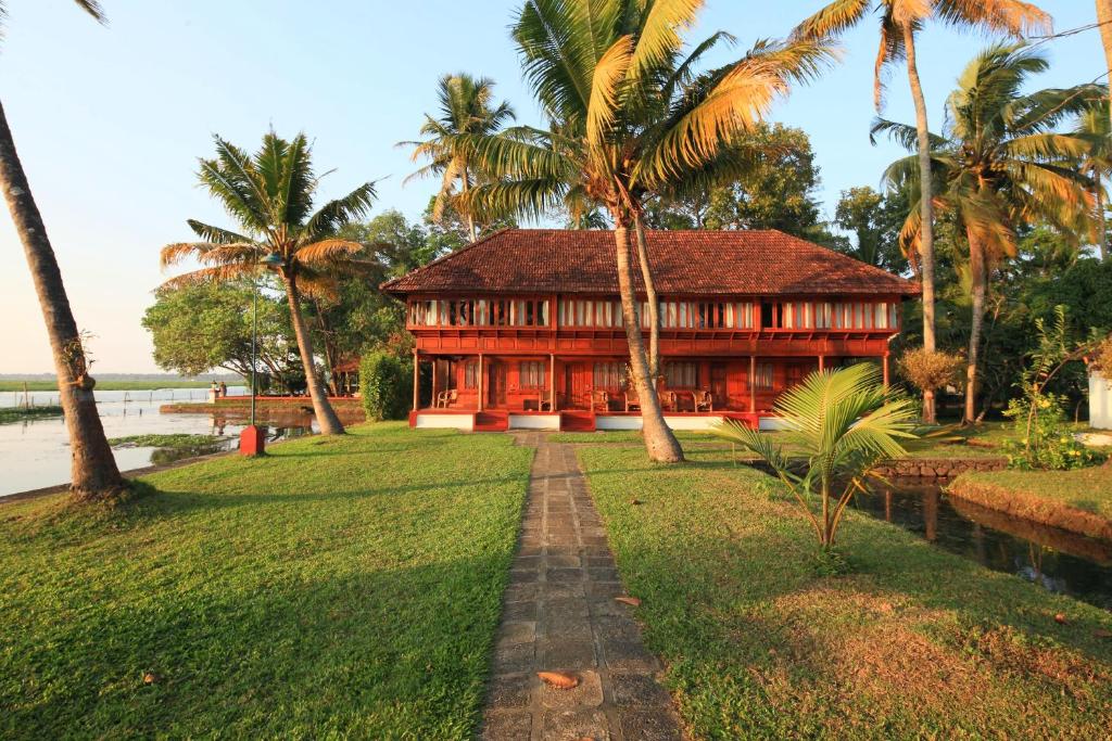 a house in the middle of a lawn with palm trees at Coconut Lagoon Kumarakom- CGH Earth in Kumarakom