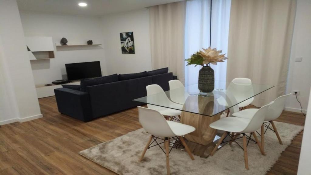 a dining room with a glass table and white chairs at Funchal Apartment in Funchal