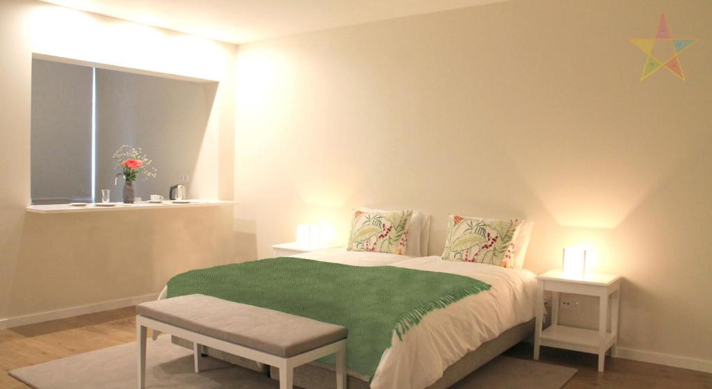 a bedroom with a bed with a green blanket at Five Elements Madeira in Funchal