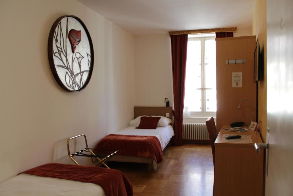 una camera d'albergo con due letti e un orologio a parete di Hostellerie du XVI Siècle a Nyon