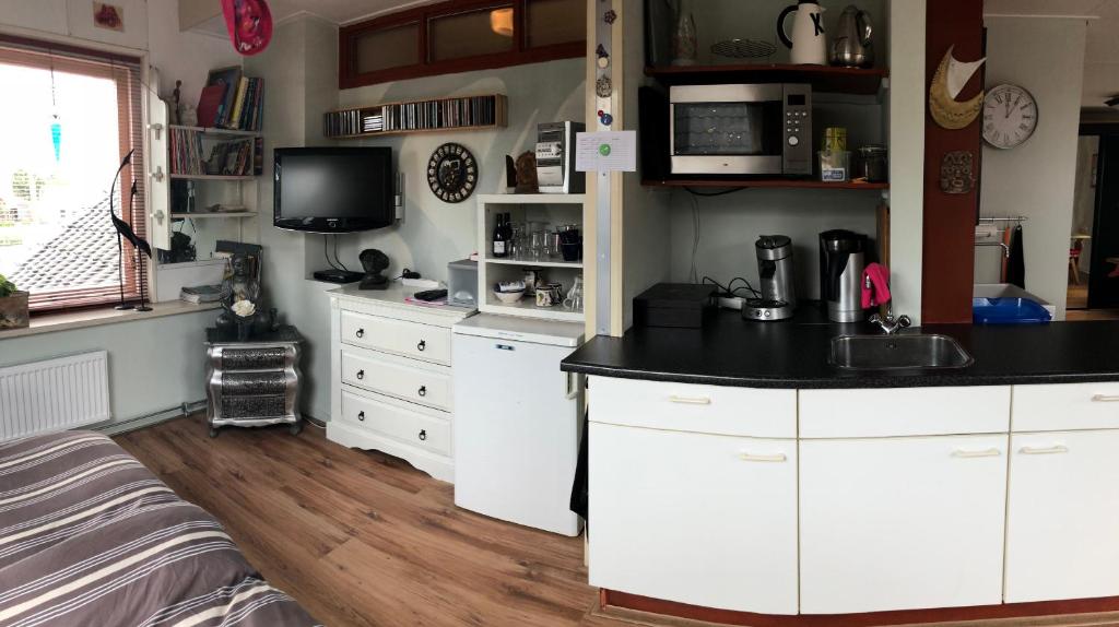 uma cozinha com armários brancos e um balcão preto em B & B Nomad em 't Zand