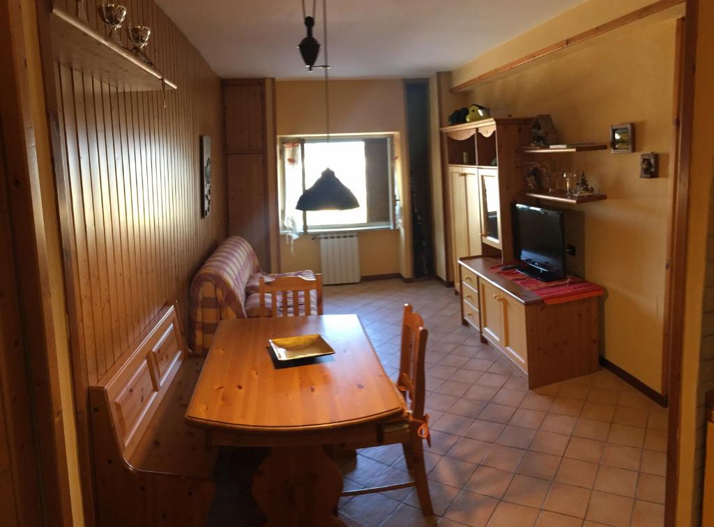 un salon avec une table en bois et une télévision dans l'établissement Villaggio dello sciatore residence paradiso, à Roccaraso
