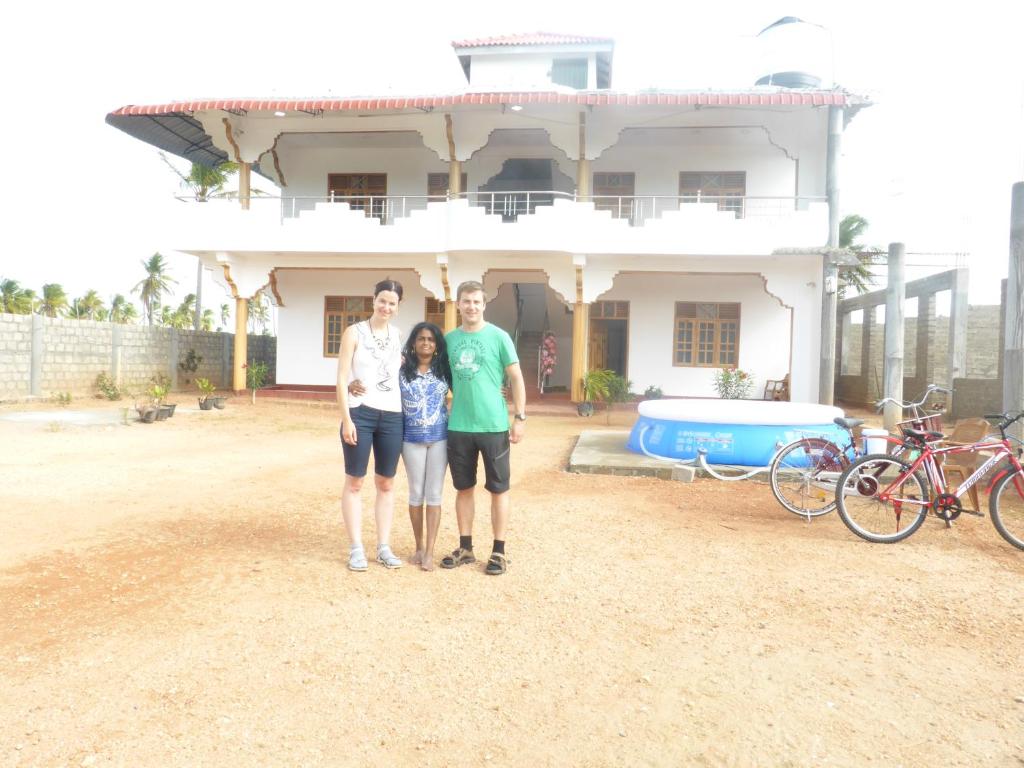 a family standing in front of a house at Nilaveli Star View Hotel in Nilaveli