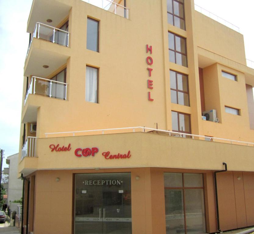 a yellow building with a red sign on it at Hotel COOP Central in Obzor