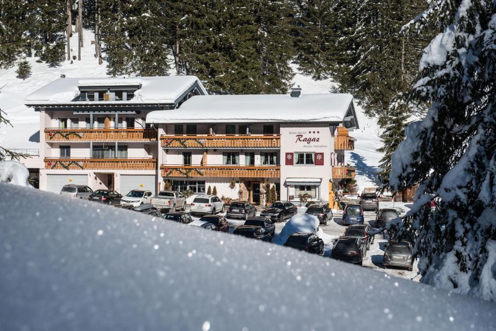 a building with cars parked in a parking lot covered in snow at Hotel Garni Ragaz in Damuls