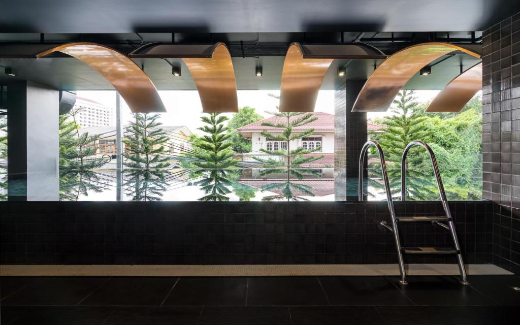 A dark-tiled pool or water feature runs along windows overlooking trees and nearby buildings.
