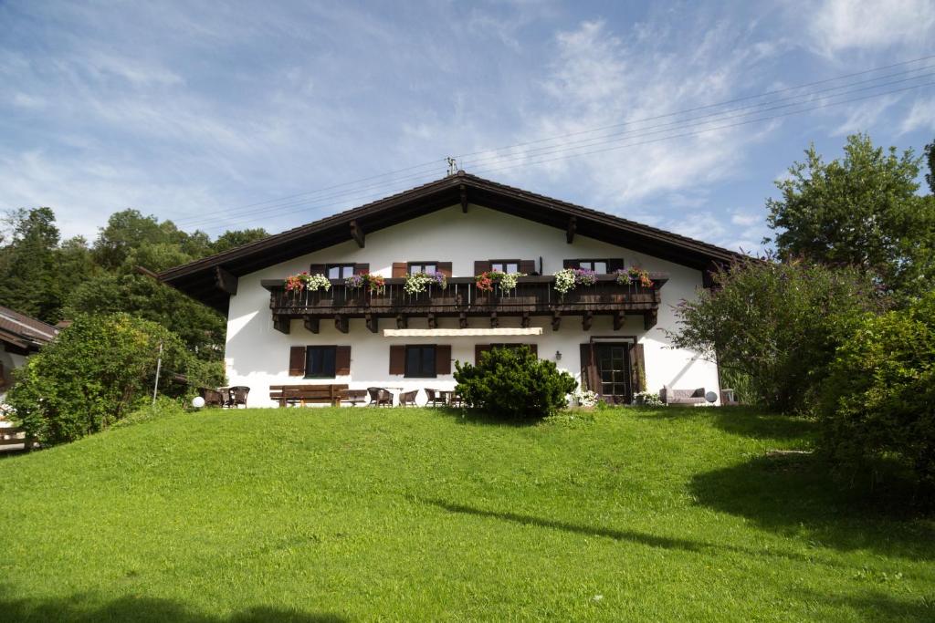 a white house with a balcony on a green lawn at Berg Blick Jugendherberge mit Privatzimmer in Kochel