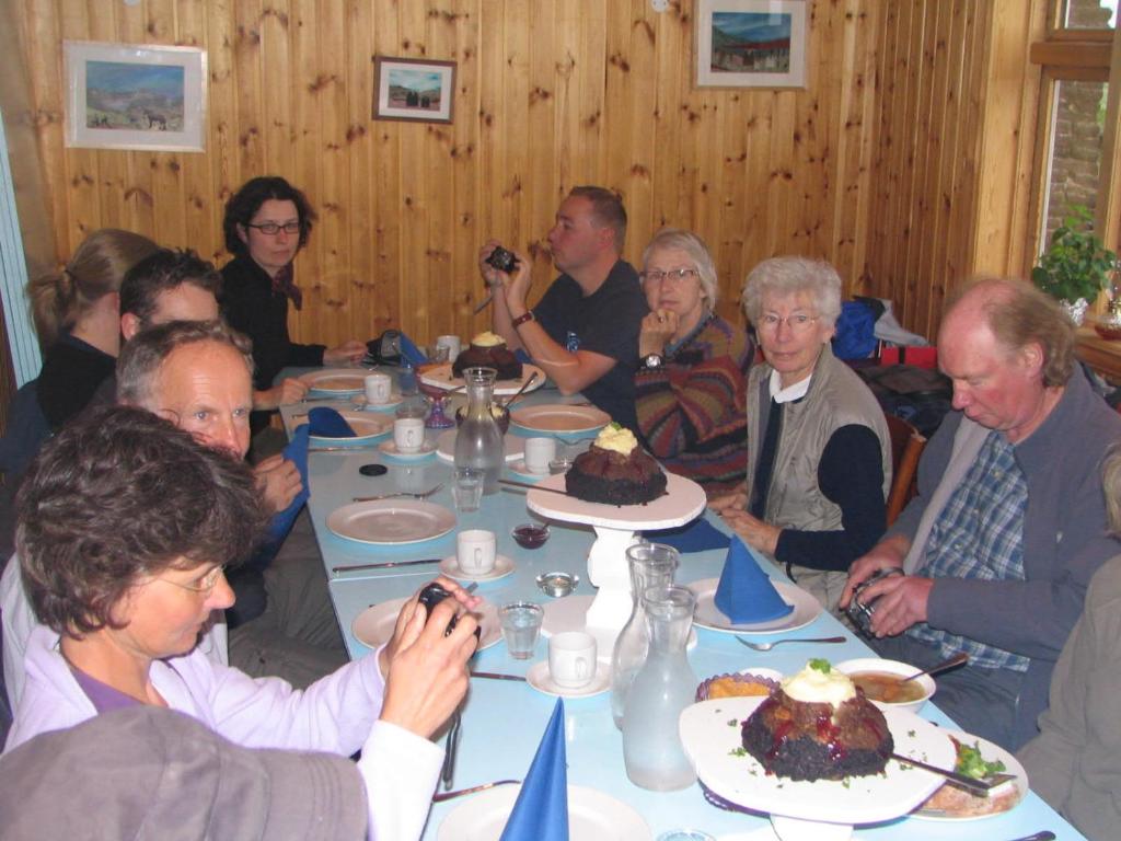 a group of people sitting around a table eating cake at Fjalladýrð Guesthouse in Modrudalur
