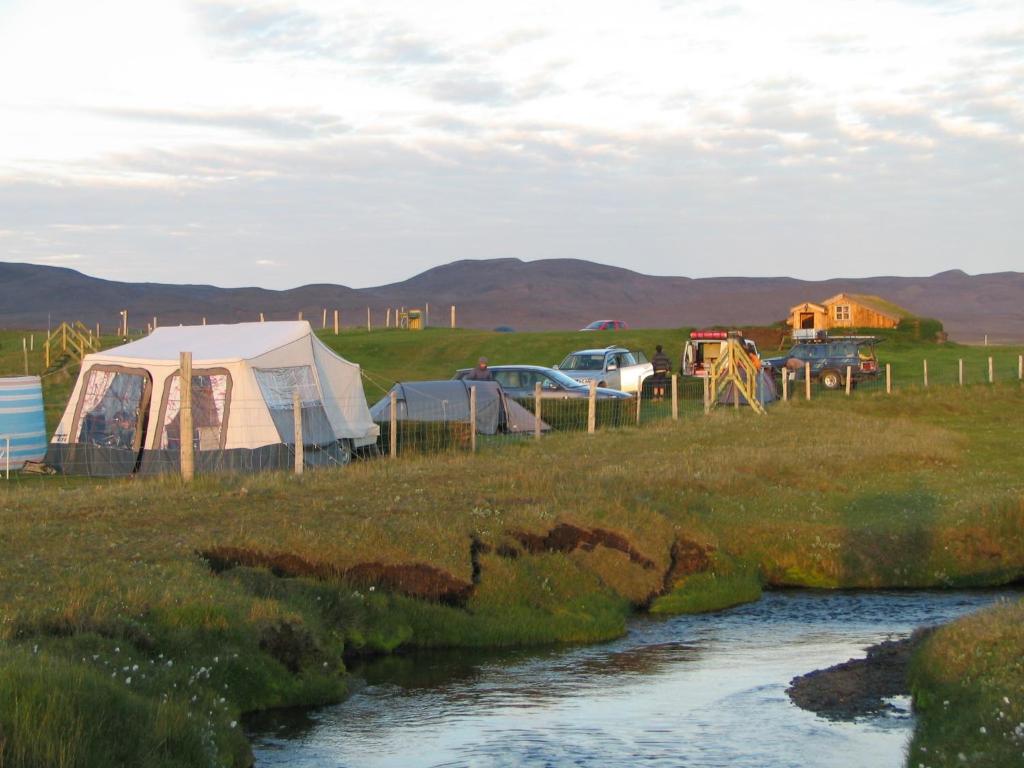 a group of tents in a field next to a river at Fjalladýrð Guesthouse in Modrudalur
