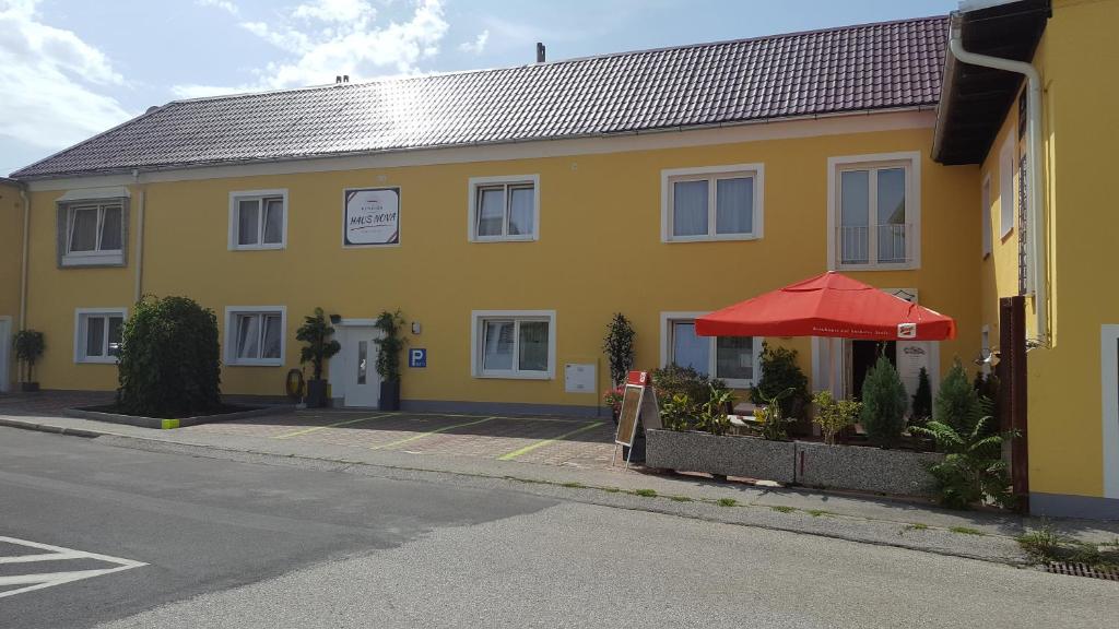 um edifício amarelo com um guarda-chuva vermelho ao lado de uma rua em Pension Haus Nova em Wiener Neustadt