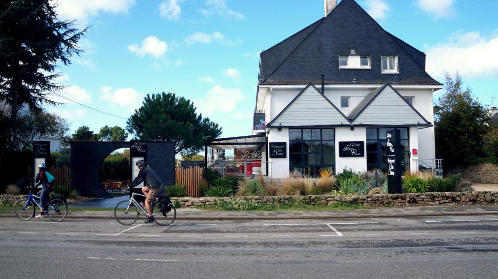 two people riding bikes in front of a house at Hotel-Restaurant Lann Roz / Côte Cuisine in Carnac