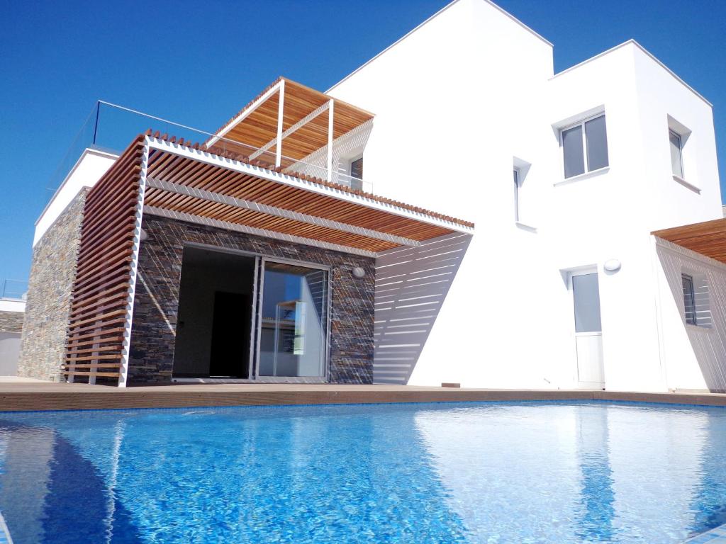 a villa with a swimming pool in front of a house at Plage Residences in Paphos City