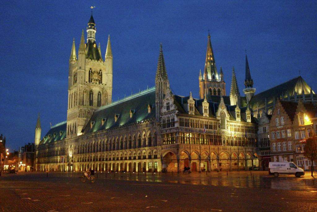 een groot gebouw met 's nachts een klokkentoren bij Hotel Gasthof 't Zweerd in Ieper