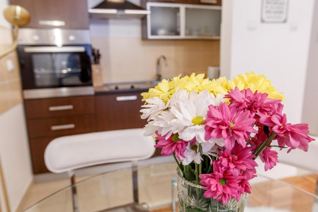 um vaso de flores sentado numa mesa numa cozinha em Linden flower Apartment em Subotica