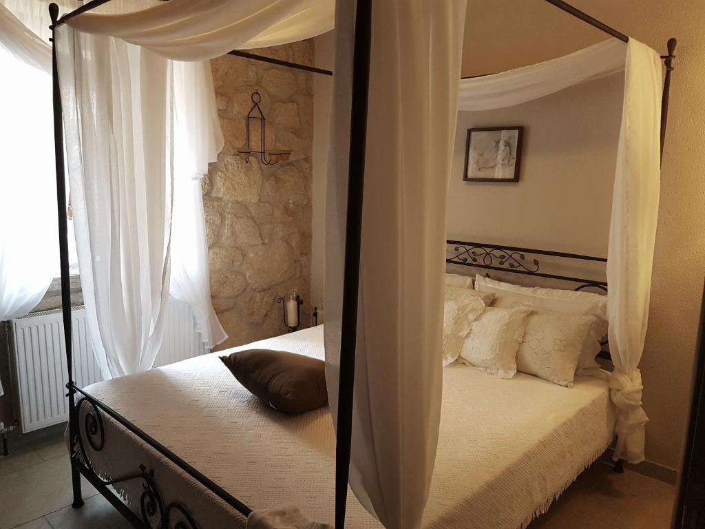 シビリにあるOikia I, Luxury Stone House in Elaniのベッドルーム(白い枕の天蓋付きベッド1台付)