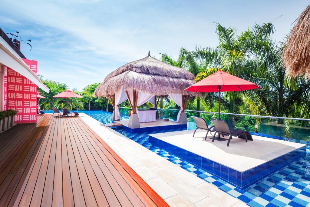 普拉亞布蘭卡的住宿－巴魯得可麥崙酒店&度假村- 全包，一个带椅子和遮阳伞的游泳池的度假酒店
