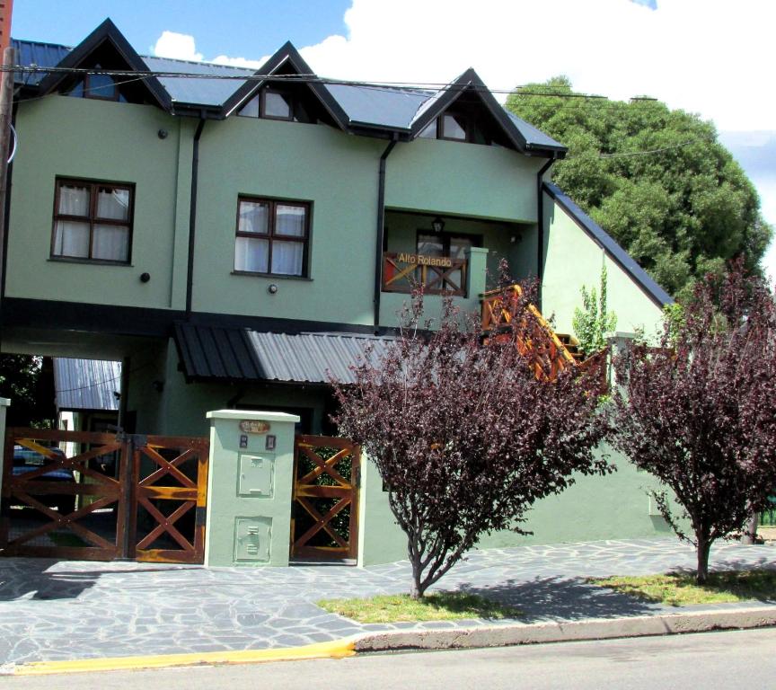 una casa verde con árboles delante de ella en Alto Rolando Apartamentos en San Carlos de Bariloche