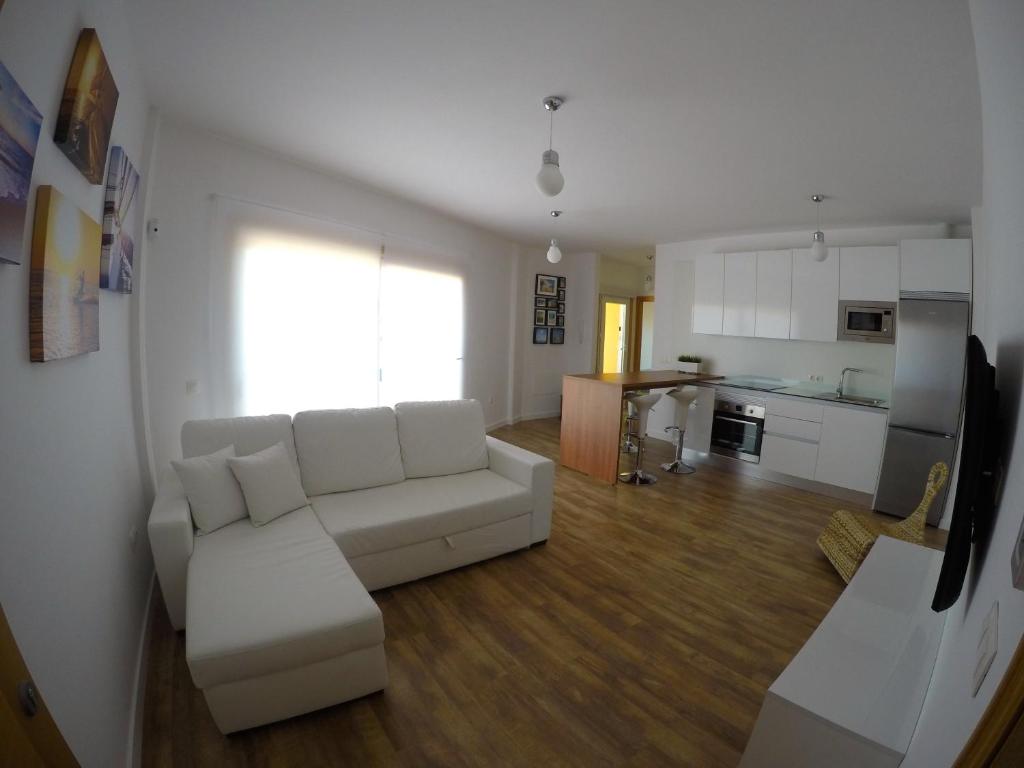 a living room with a white couch and a kitchen at Cotillo Beach & Sport in El Cotillo