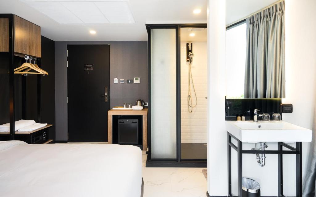 A compact guest room combines a bed, open vanity, shower enclosure, wardrobe and tea station.