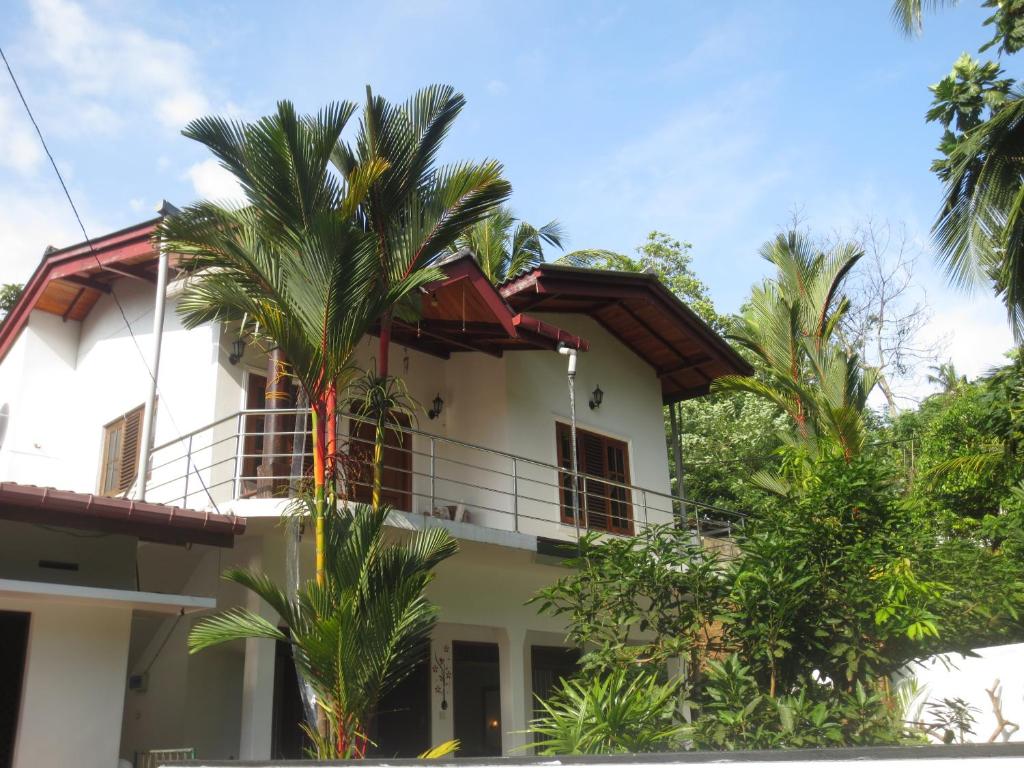 a house with palm trees in front of it at Jungle Holiday Home in Hikkaduwa