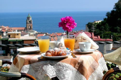 une table avec une assiette de nourriture et deux verres de jus d'orange dans l'établissement Villa Lara Hotel, à Amalfi