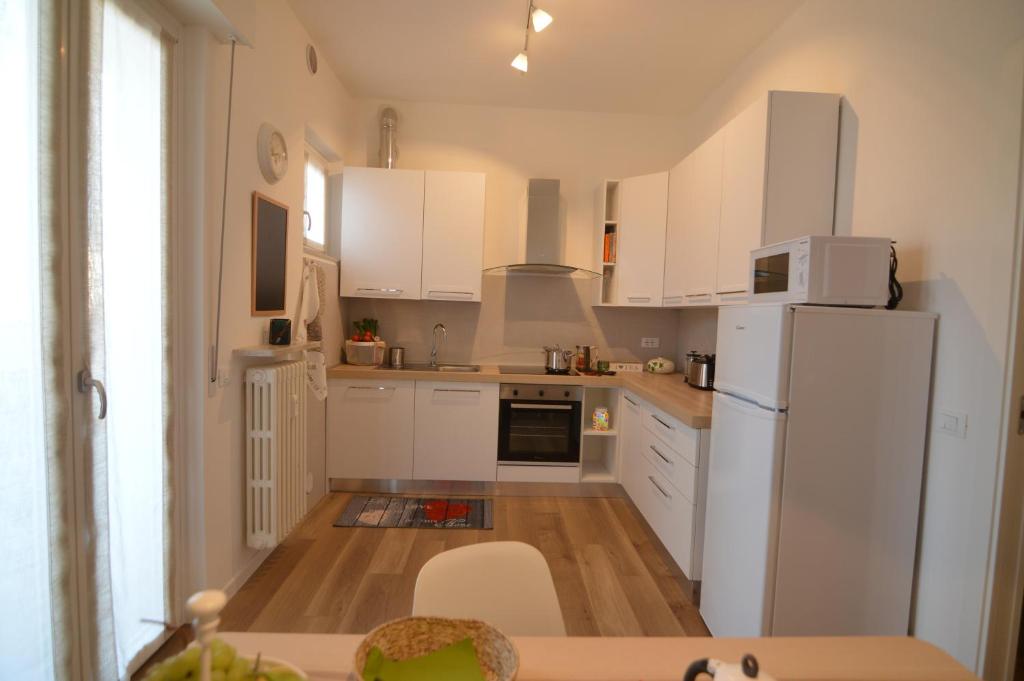 La cuisine est équipée de placards blancs et d'un réfrigérateur blanc. dans l'établissement Via Da Velo 8 appartamento, à Vérone