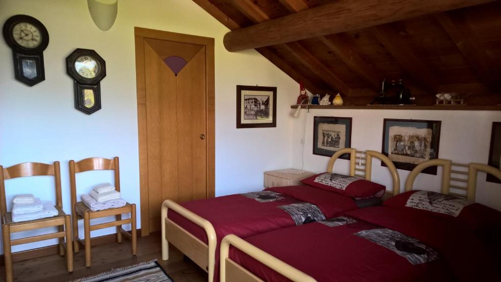 1 dormitorio con 1 cama, 2 sillas y reloj en B&B San Giorgio, en Sovramonte