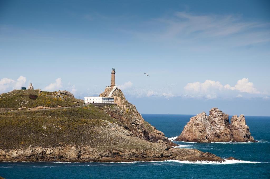 un faro en una pequeña isla en el océano en RO Apartamentos Pampin Ponte Do Porto, en A Ponte do Porto