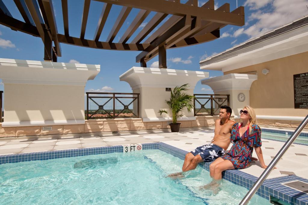 a man and a woman sitting in a swimming pool at Plaza Suites On International Drive Near Universal Epic in Orlando