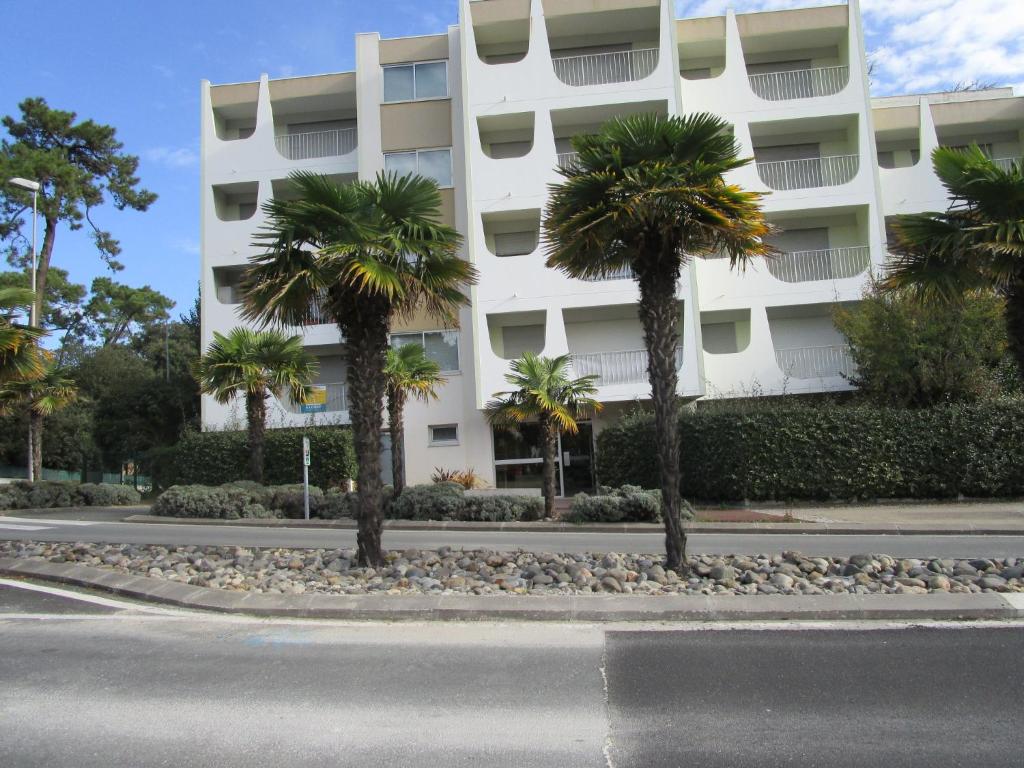 un bâtiment avec des palmiers devant une rue dans l'établissement Residence St PALAIS, à Saint-Palais-sur-Mer