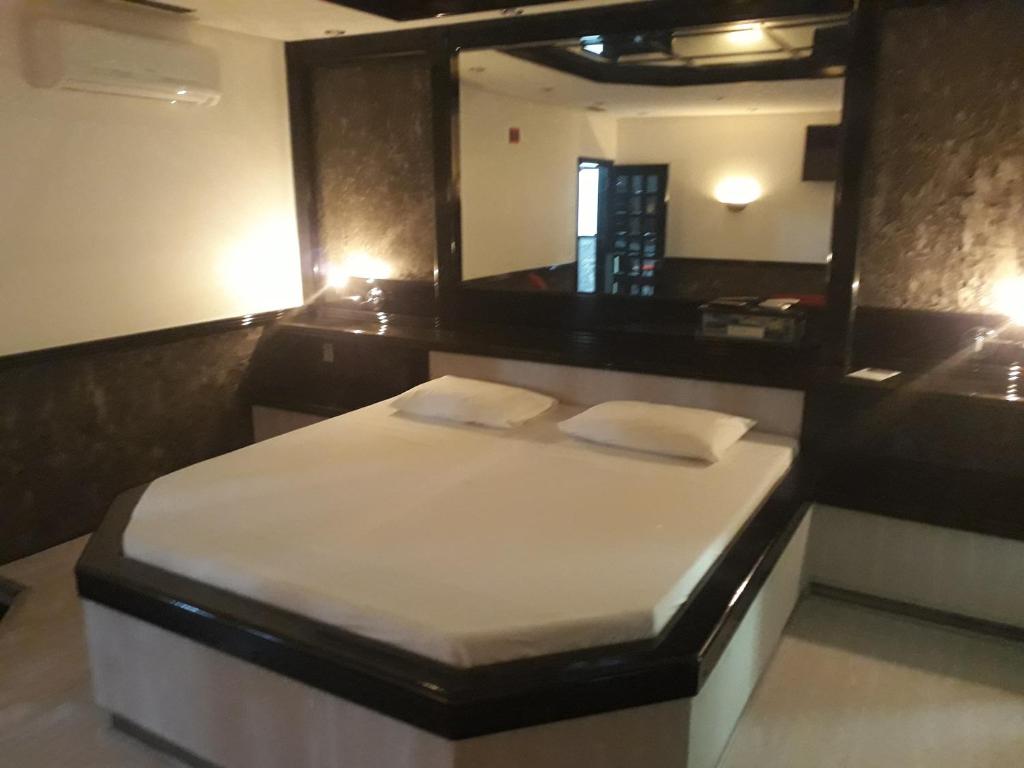 a bed in a room with a large mirror at Motel Casa Branca in Blumenau